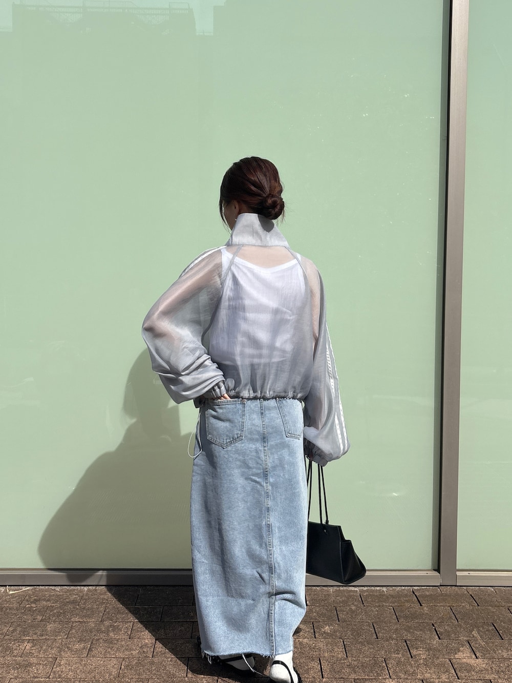 グレー系のブルゾン、ブルー系のデニムスカート、ホワイト系のタンクトップを着用したレディースの春コーディネートの3枚目の写真