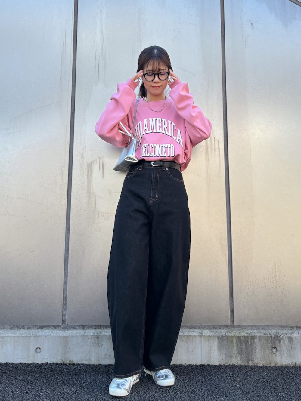 ピンク系のスウェット、ブラック系のデニムパンツ、シルバー系のスニーカーを着用したレディースの秋コーディネートの2枚目の写真