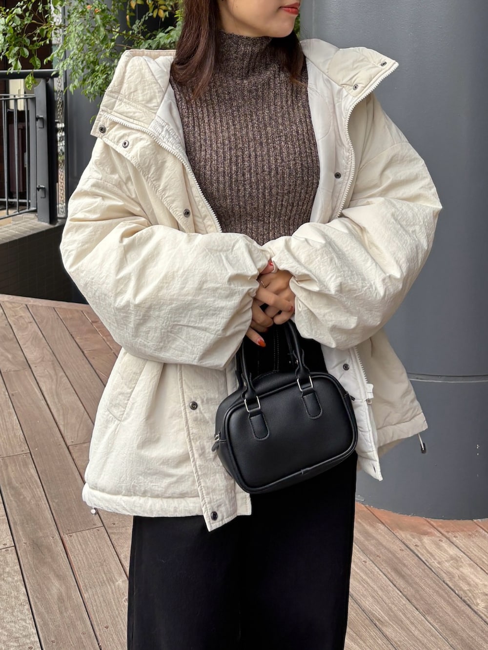 ブラウン系のニット/セーター、ホワイト系のダウンジャケット/コート、ブラック系のデニムパンツを着用したレディースの秋コーディネートの2枚目の写真