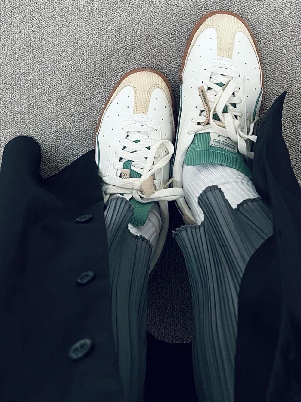 ベージュ系のチェスターコート、ブラック系のワンピース、ホワイト系のスニーカーを着用したレディースの冬コーディネートの3枚目の写真