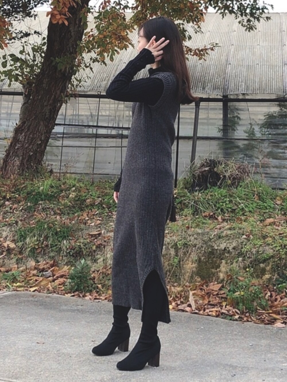 グレー系のワンピース、ブラック系のニット/セーター、ブラック系のブーツを着用したレディースの冬コーディネートの2枚目の写真
