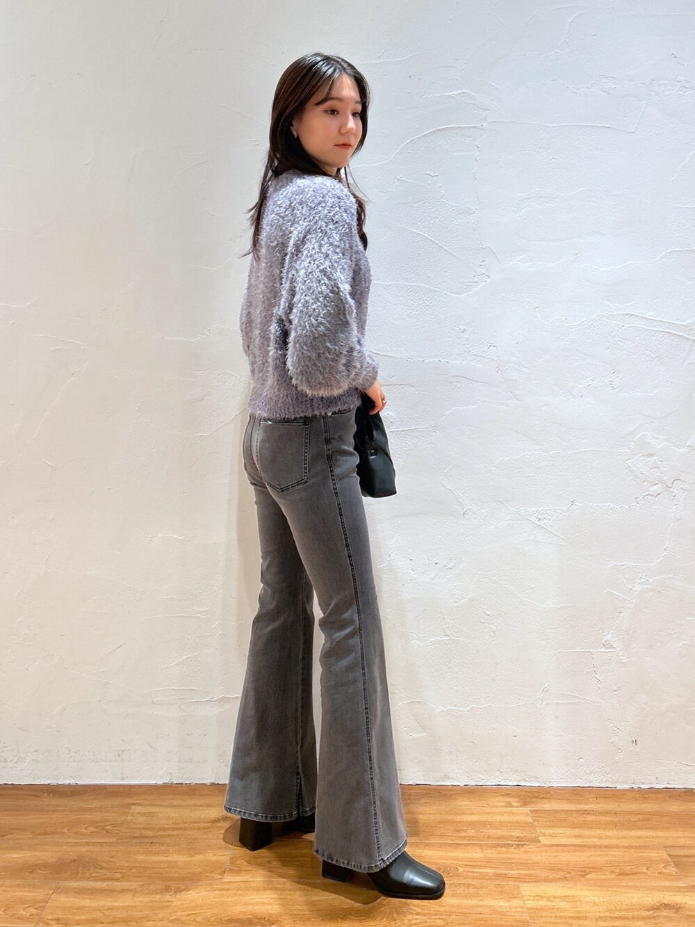 グレー系のニット/セーター、ブラック系のデニムパンツ、ブラック系のブーツを着用したレディースの冬コーディネートの2枚目の写真