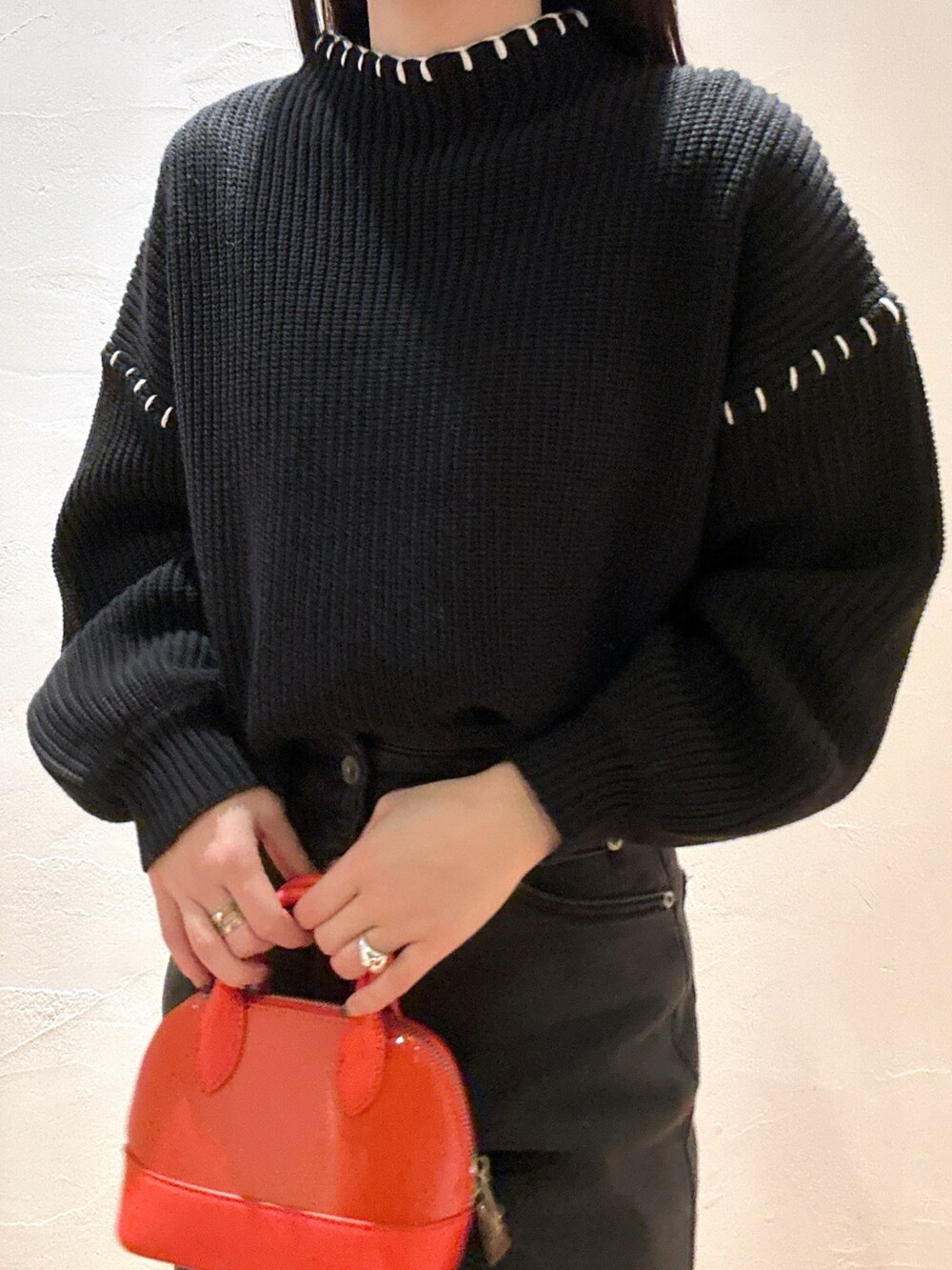 ブラック系のニット/セーター、ブラック系のデニムパンツ、オレンジ系のショルダーバッグを着用したレディースの冬コーディネートの4枚目の写真