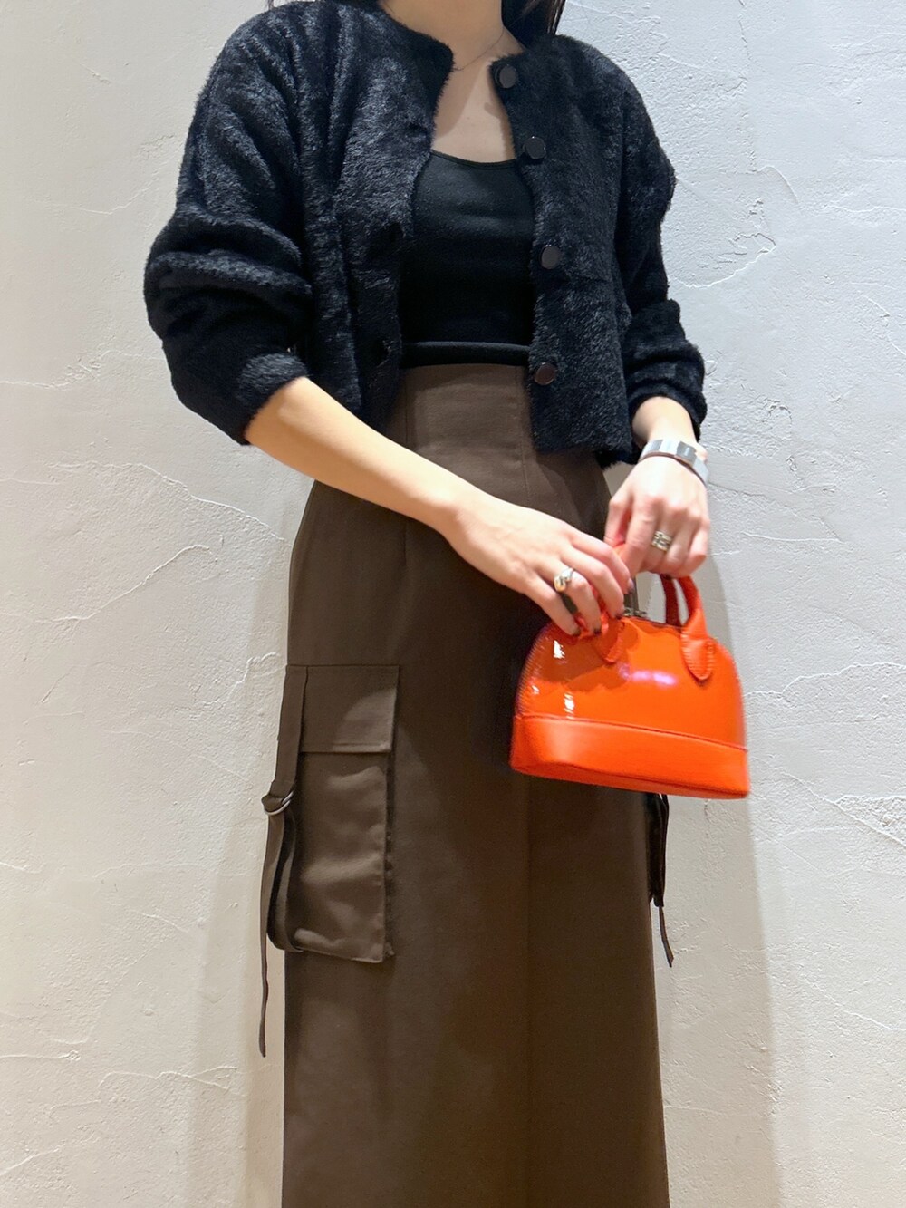 ブラック系のカーディガン/ボレロ、ブラウン系のスカート、オレンジ系のショルダーバッグを着用したレディースの秋コーディネートの4枚目の写真