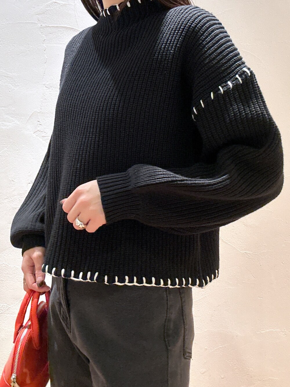 ブラック系のニット/セーター、ブラック系のデニムパンツ、オレンジ系のショルダーバッグを着用したレディースの冬コーディネートの5枚目の写真