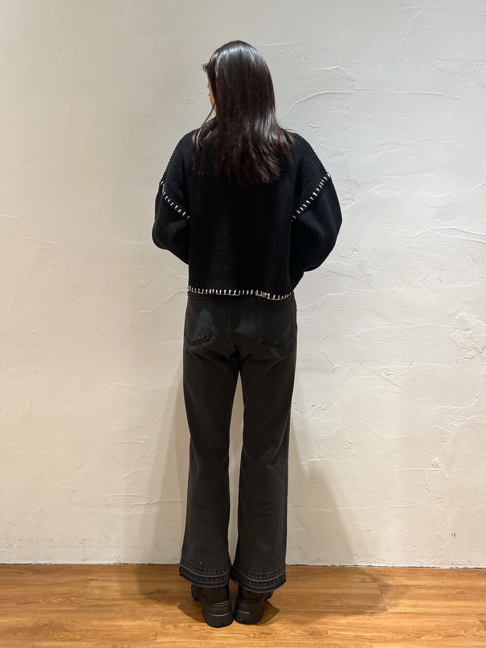 ブラック系のニット/セーター、ブラック系のデニムパンツ、オレンジ系のショルダーバッグを着用したレディースの冬コーディネートの3枚目の写真