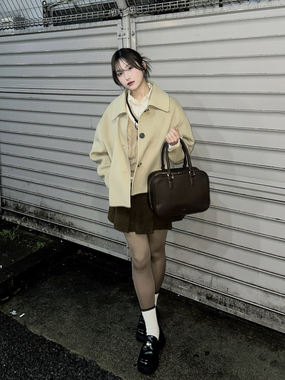 ブラウン系のスカート、ブラック系のローファー、ベージュ系のベストを着用したレディースの冬コーディネートの2枚目の写真