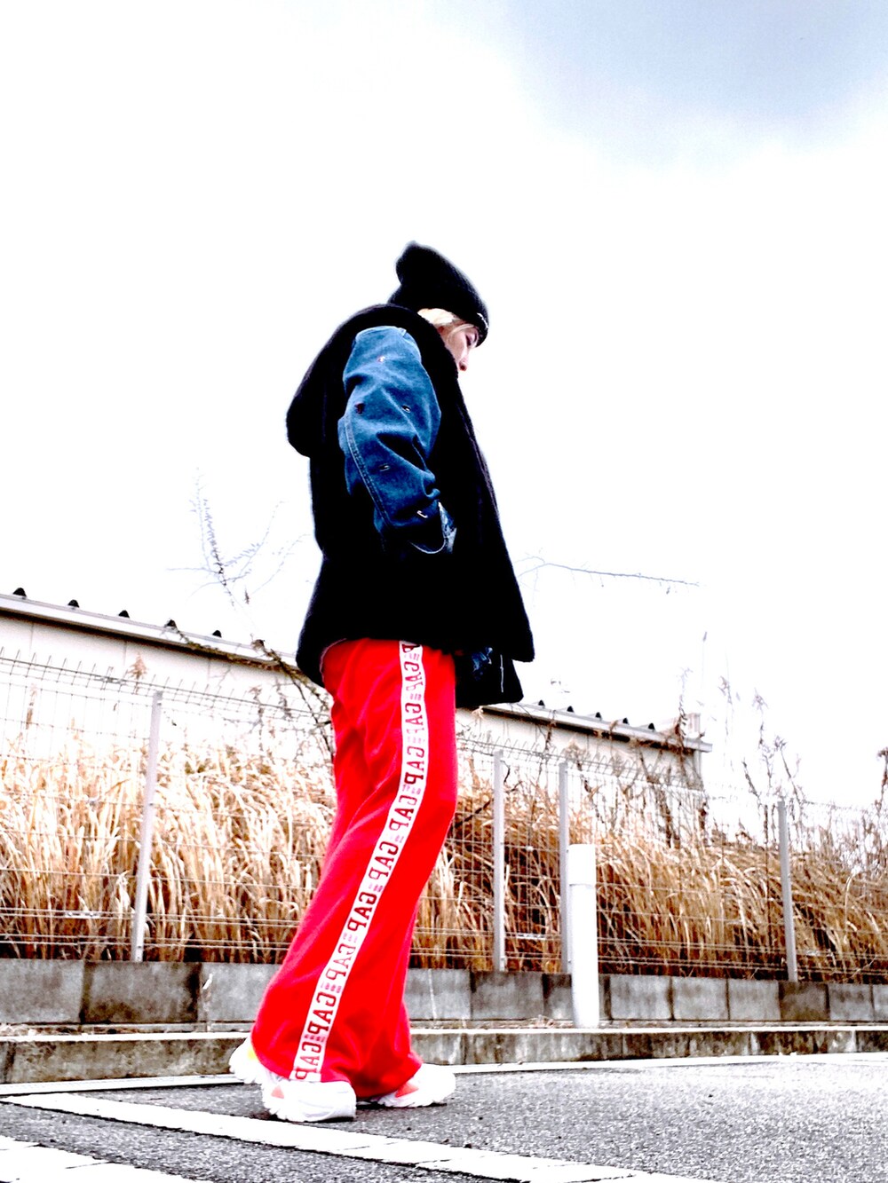 ブルー系のデニムジャケット、ブラック系のその他アウター、レッド系のスウェットパンツを着用したレディースの冬コーディネートの2枚目の写真