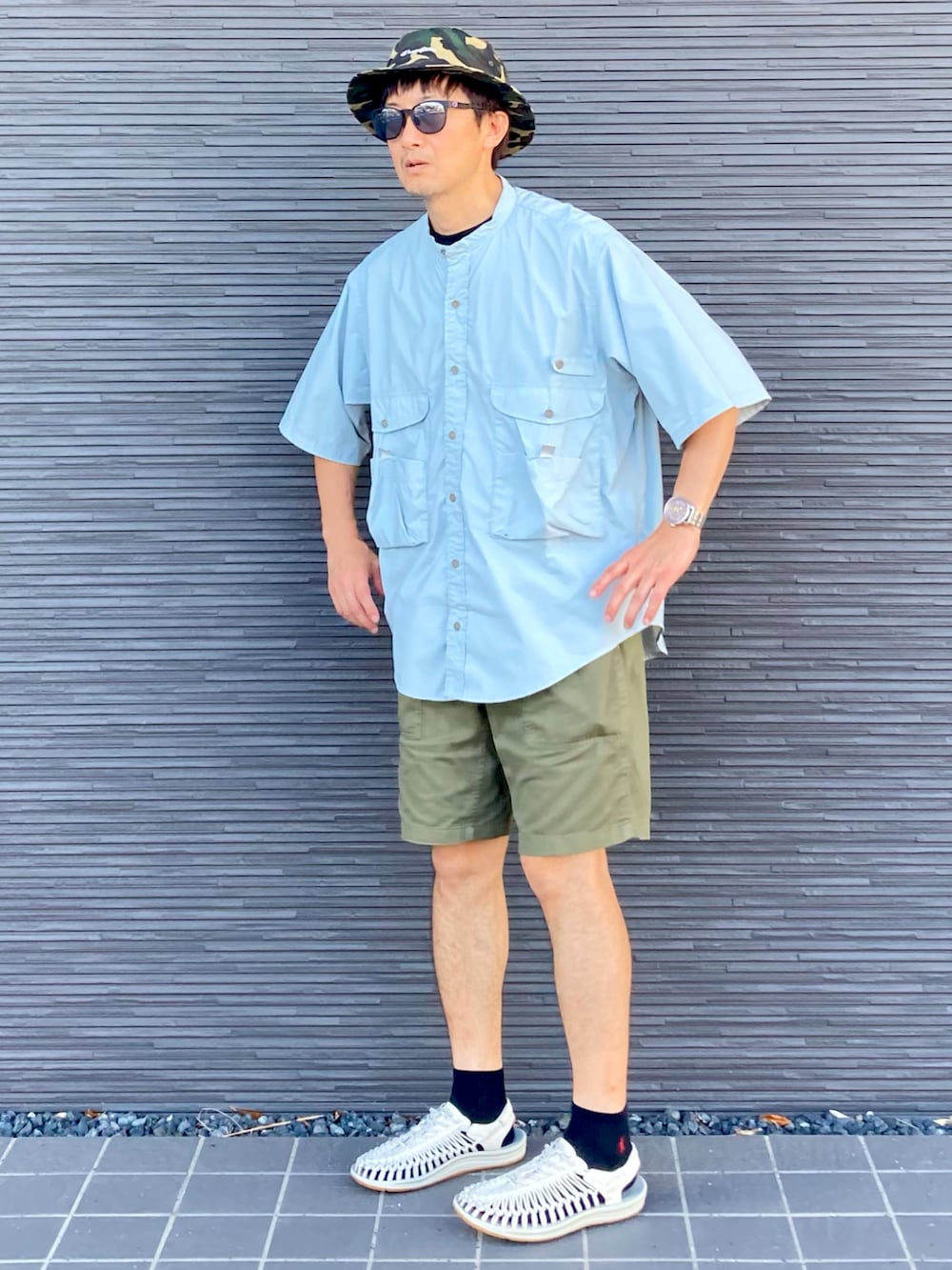 ブルー系のシャツ/ブラウス、グリーン系のカーゴパンツ、ホワイト系のサンダルを着用したメンズの夏コーディネートの2枚目の写真
