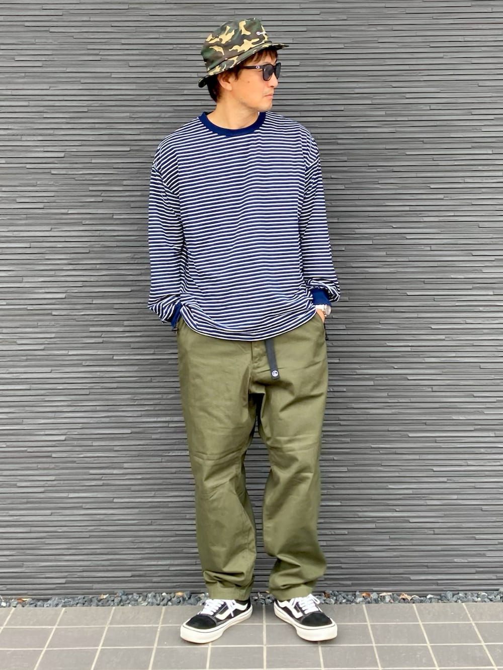 ブルー系のTシャツ/カットソー、グリーン系のチノパンツ、ブラック系のスニーカーを着用したメンズの秋コーディネートの2枚目の写真