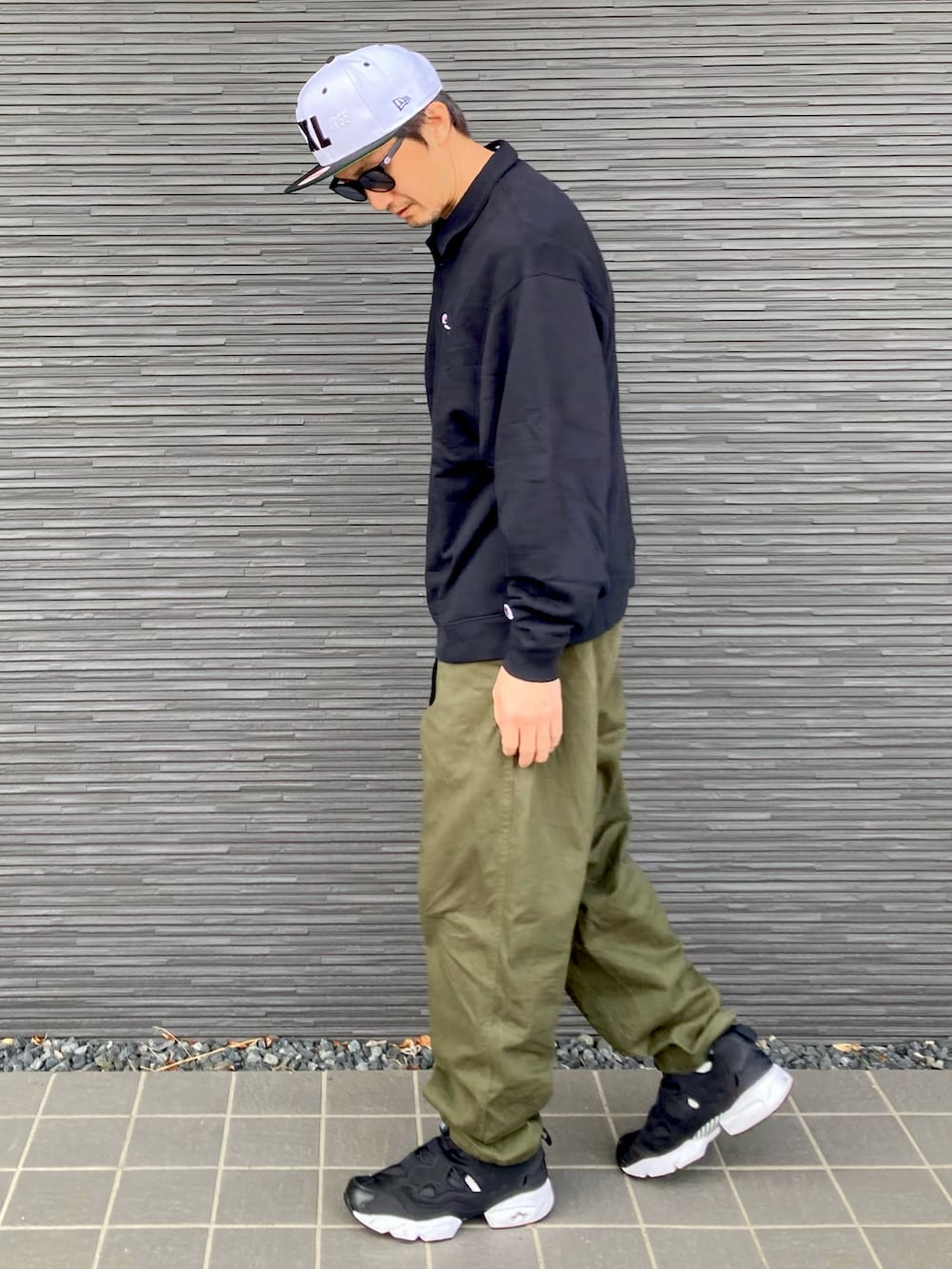 ブラック系のスウェット、グリーン系のチノパンツ、ブラック系のスニーカーを着用したメンズの春コーディネートの2枚目の写真