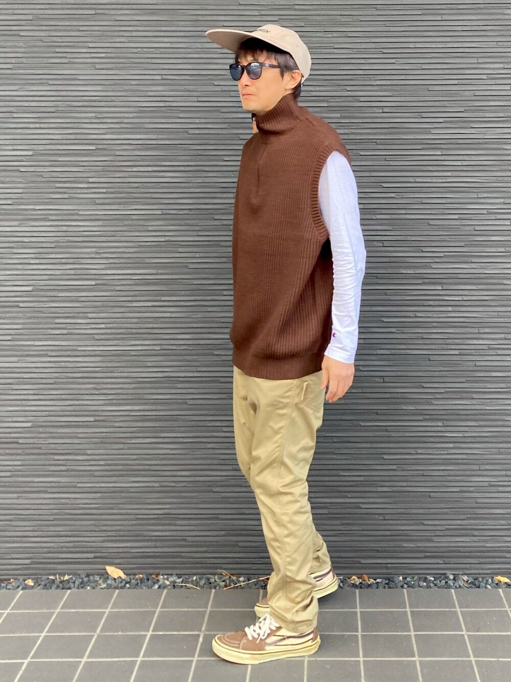 ブラウン系のベスト、ホワイト系のTシャツ/カットソー、ベージュ系のチノパンツを着用したメンズの春コーディネートの3枚目の写真