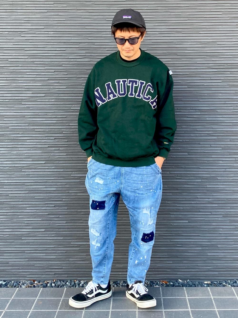 グリーン系のスウェット、ブルー系のデニムパンツ、ブラック系のスニーカーを着用したメンズの秋コーディネートの3枚目の写真