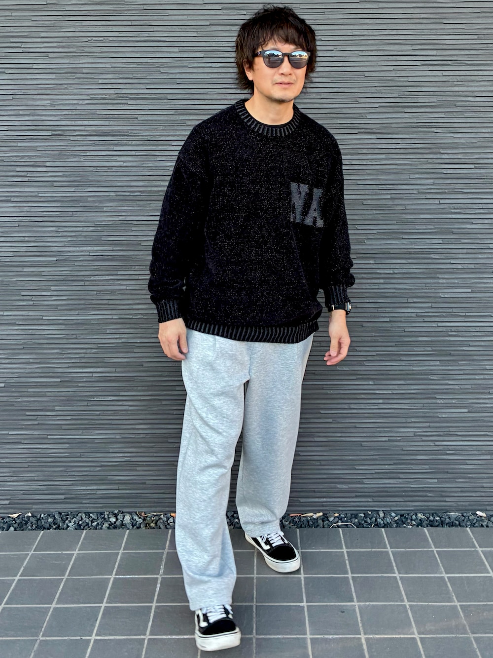 ブラック系のスニーカー、ブラック系のニット/セーター、グレー系のスウェットパンツを着用したメンズの春コーディネートの3枚目の写真