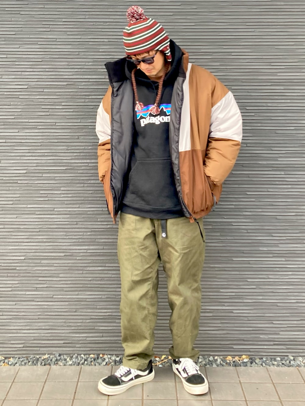 ベージュ系のブルゾン、ブラック系のパーカー、グリーン系のチノパンツを着用したメンズの冬コーディネートの2枚目の写真