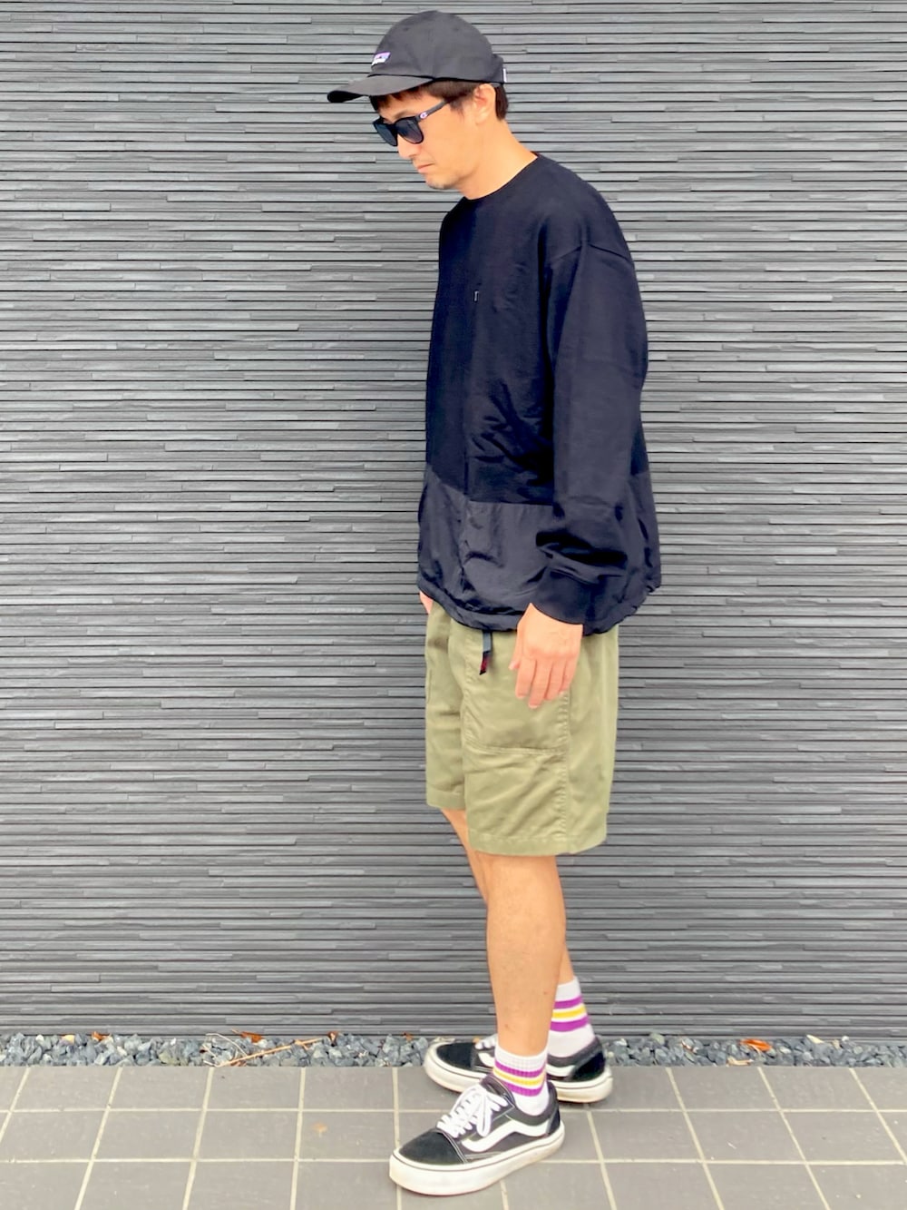 ブラック系のトップス、グリーン系のカーゴパンツ、ブラック系のスニーカーを着用したメンズの春コーディネートの3枚目の写真