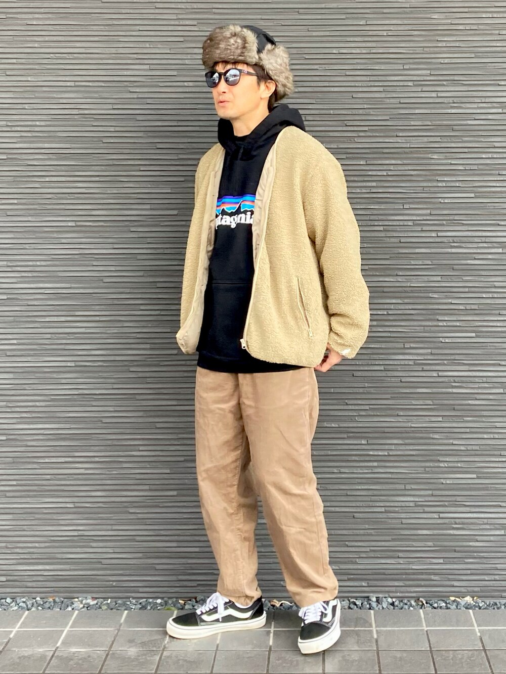 ベージュ系のノーカラージャケット、ブラック系のパーカー、ブラウン系のその他パンツを着用したメンズの冬コーディネートの2枚目の写真