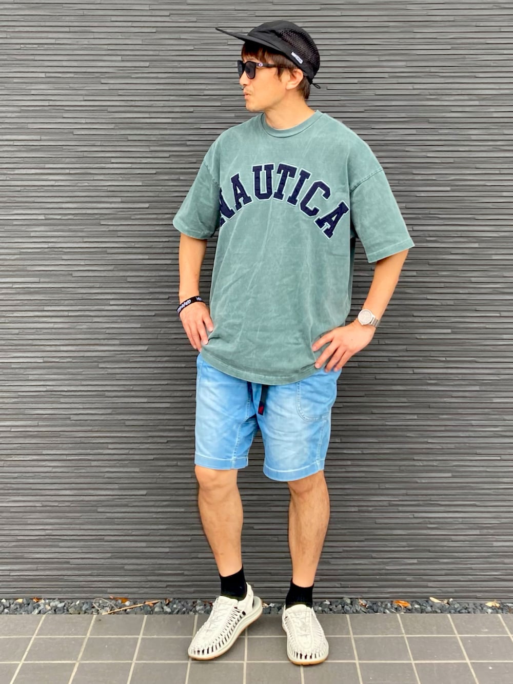 グリーン系のTシャツ/カットソー、ブルー系のデニムパンツ、ホワイト系のサンダルを着用したメンズの夏コーディネートの3枚目の写真