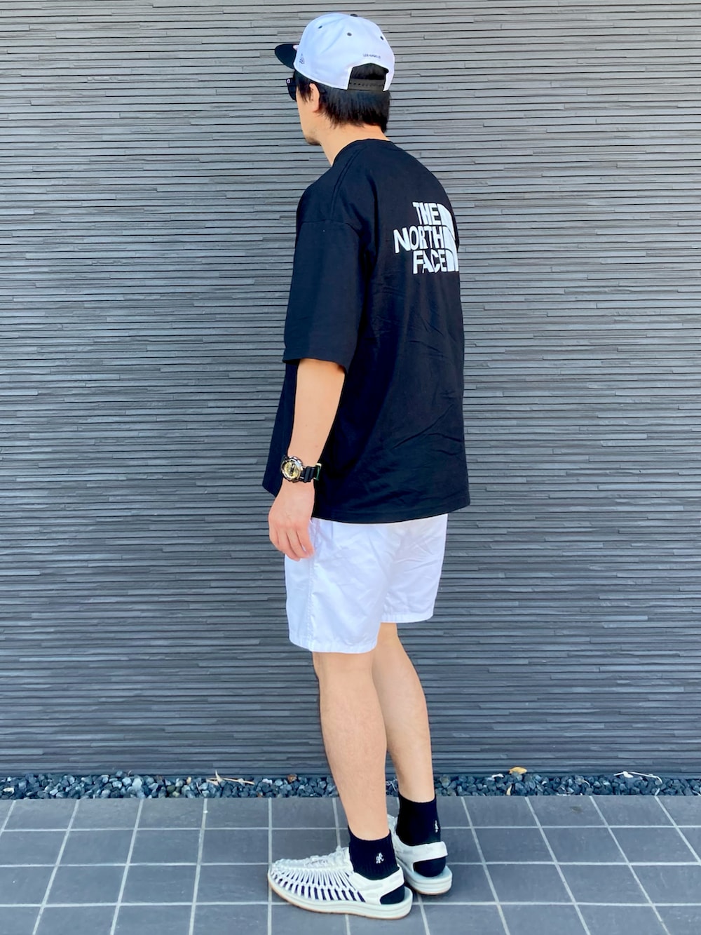 ブラック系のTシャツ/カットソー、ホワイト系のサンダル、ホワイト系のパンツを着用したメンズの夏コーディネートの3枚目の写真