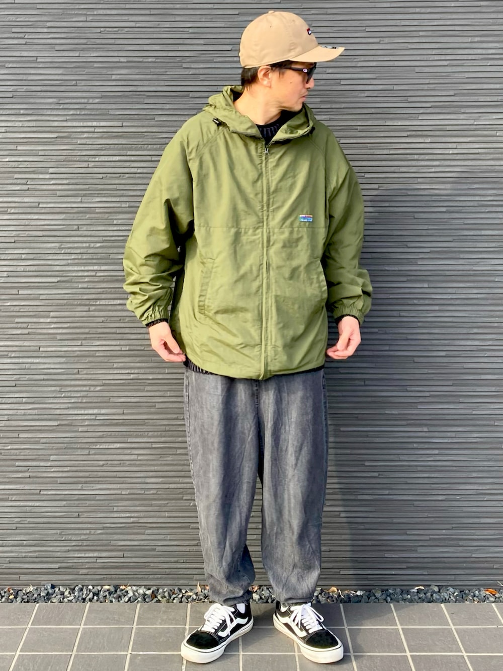 グリーン系のナイロンジャケット、ブラック系のニット/セーター、ブラック系のその他パンツを着用したメンズの春コーディネートの5枚目の写真