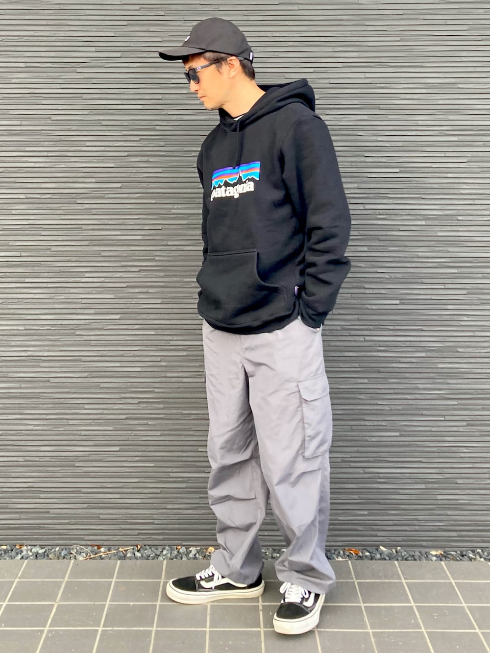 ブラック系のパーカー、グレー系のパンツ、ブラック系のスニーカーを着用したメンズの秋コーディネートの3枚目の写真