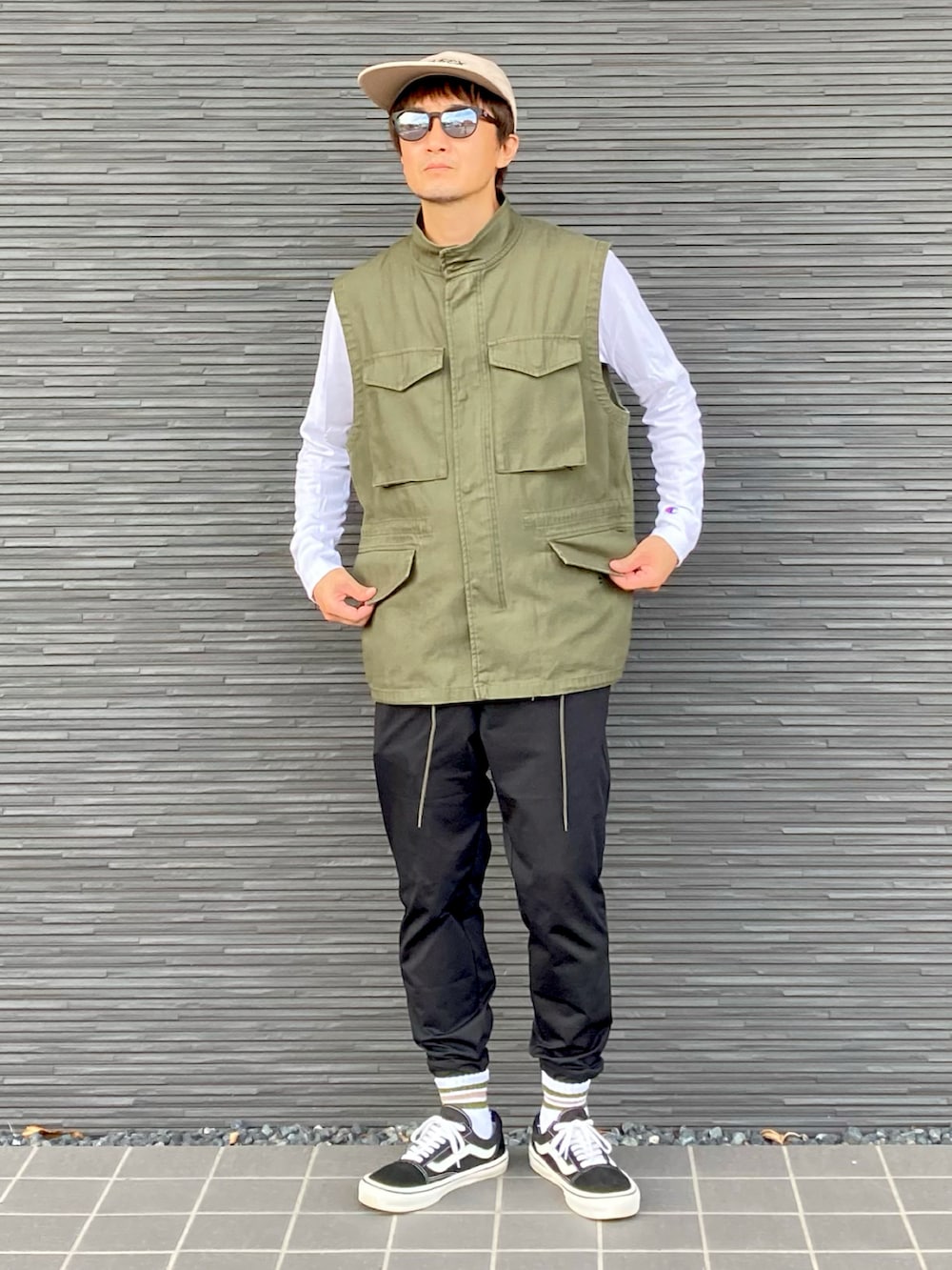 グリーン系のベスト、ホワイト系のTシャツ/カットソー、ブラック系のパンツを着用したメンズの秋コーディネートの3枚目の写真