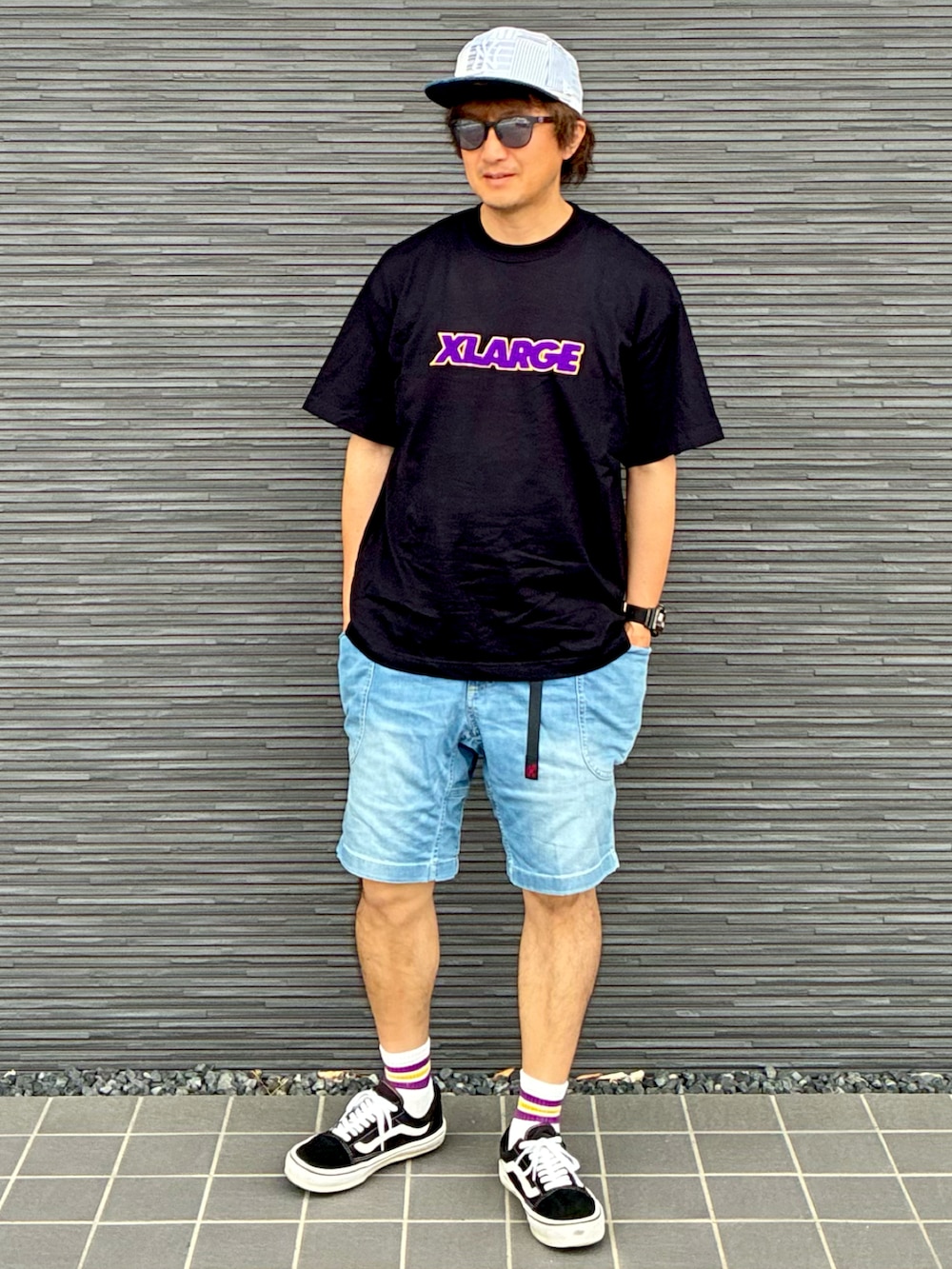 ブラック系のスニーカー、ブラック系のTシャツ/カットソー、ブルー系のデニムパンツを着用したメンズの夏コーディネートの3枚目の写真