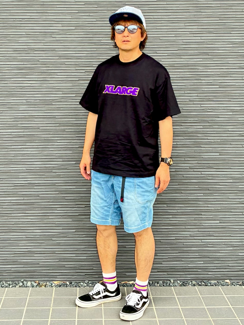 ブラック系のスニーカー、ブラック系のTシャツ/カットソー、ブルー系のデニムパンツを着用したメンズの夏コーディネートの2枚目の写真