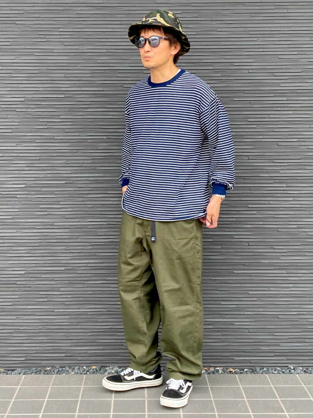 ブルー系のTシャツ/カットソー、グリーン系のチノパンツ、ブラック系のスニーカーを着用したメンズの秋コーディネートの3枚目の写真