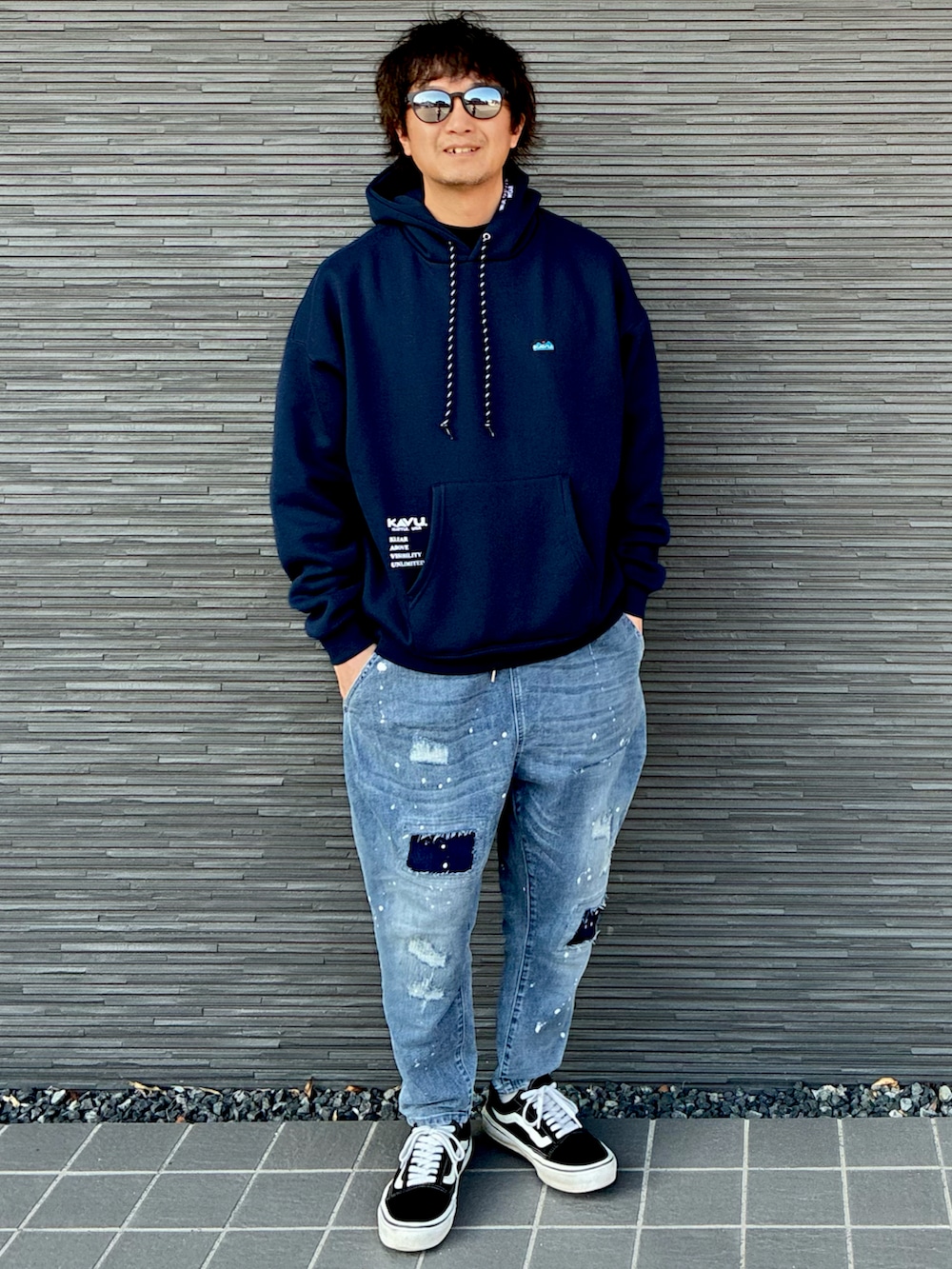 ブルー系のパーカー、ブラック系のスニーカー、ブルー系のデニムパンツを着用したメンズの春コーディネートの3枚目の写真