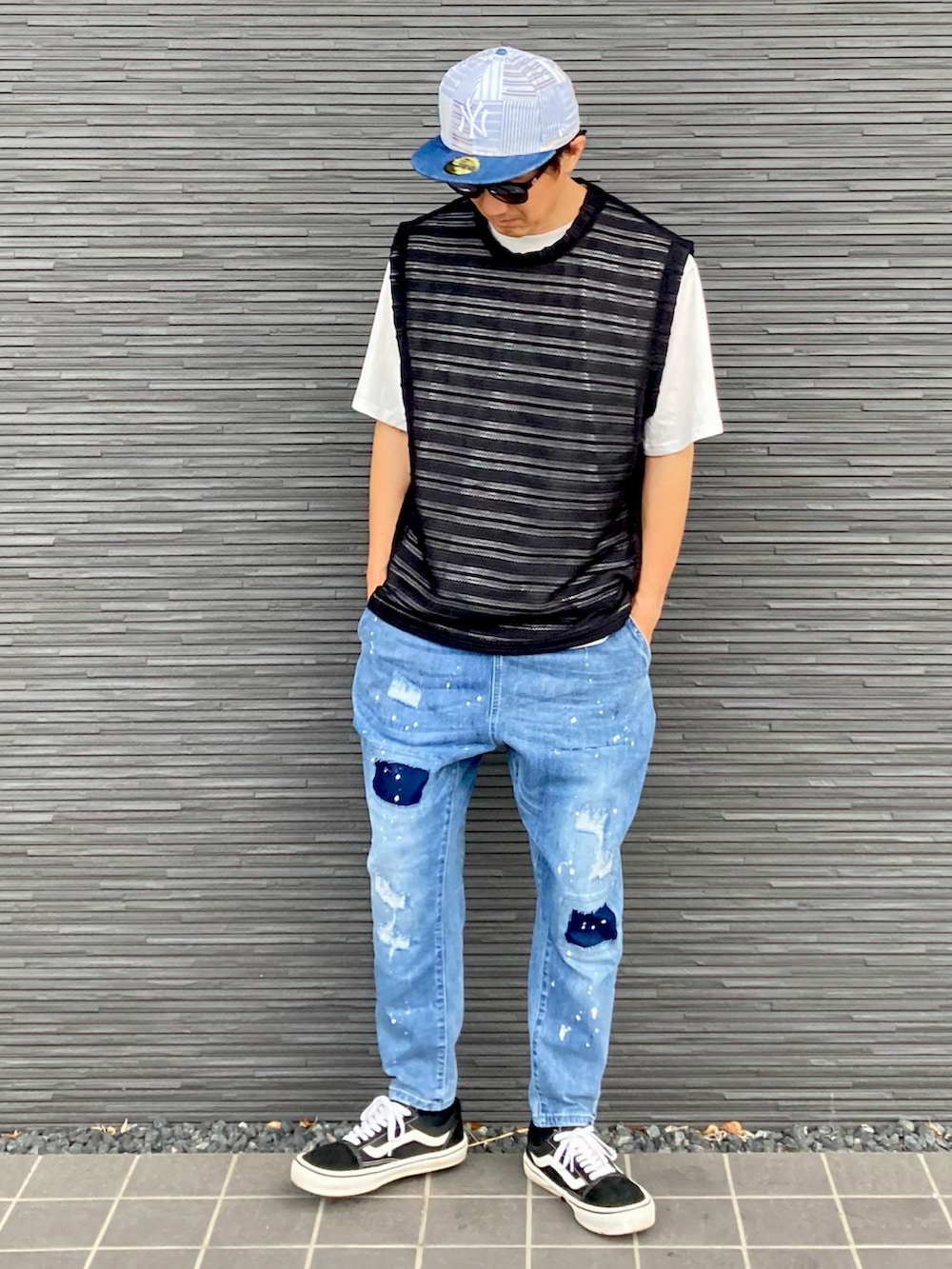 ブラック系のベスト、ブルー系のデニムパンツ、ブラック系のスニーカーを着用したメンズの夏コーディネートの2枚目の写真