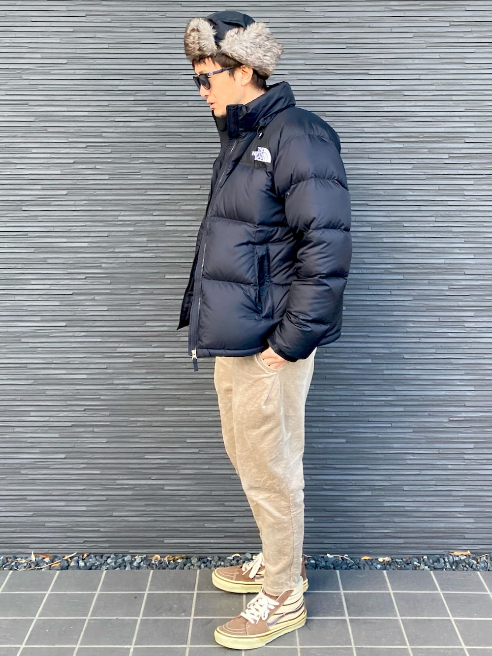 ブラック系のダウンジャケット/コート、ブラウン系のニット/セーター、ベージュ系のその他パンツを着用したメンズの冬コーディネートの3枚目の写真