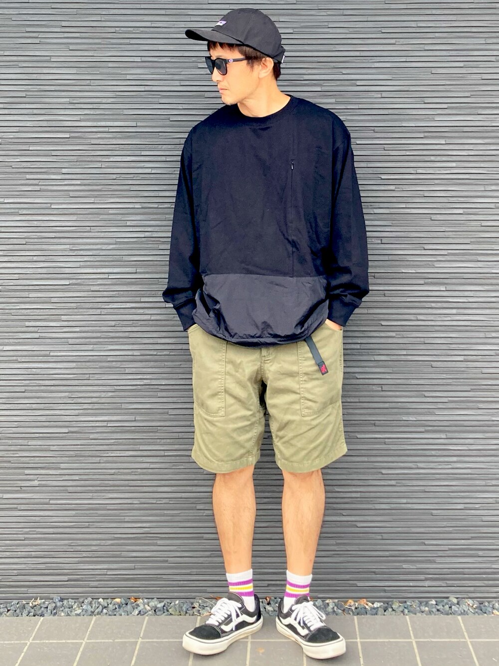 ブラック系のトップス、グリーン系のカーゴパンツ、ブラック系のスニーカーを着用したメンズの春コーディネートの2枚目の写真