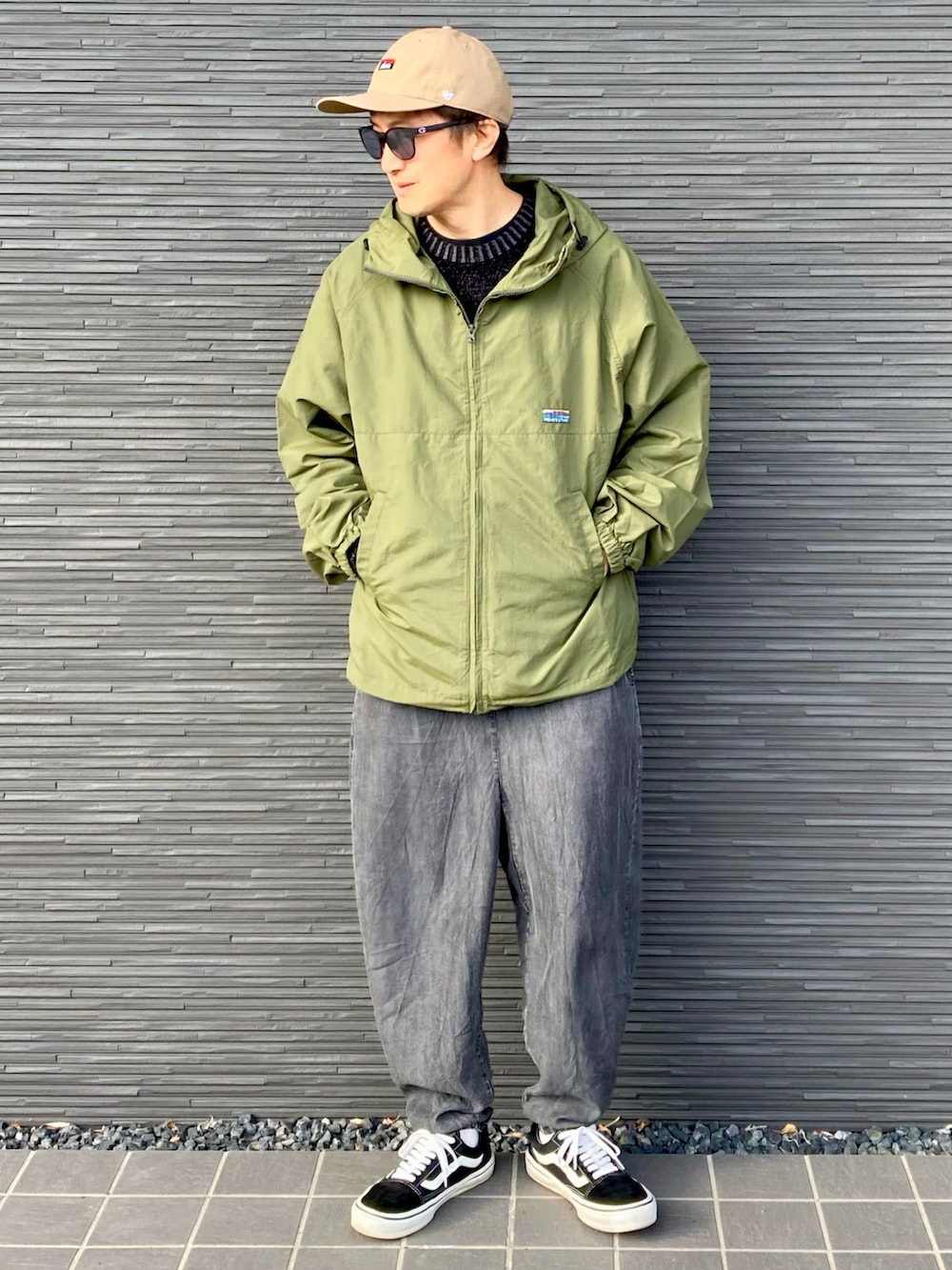 グリーン系のナイロンジャケット、ブラック系のニット/セーター、ブラック系のその他パンツを着用したメンズの春コーディネートの2枚目の写真