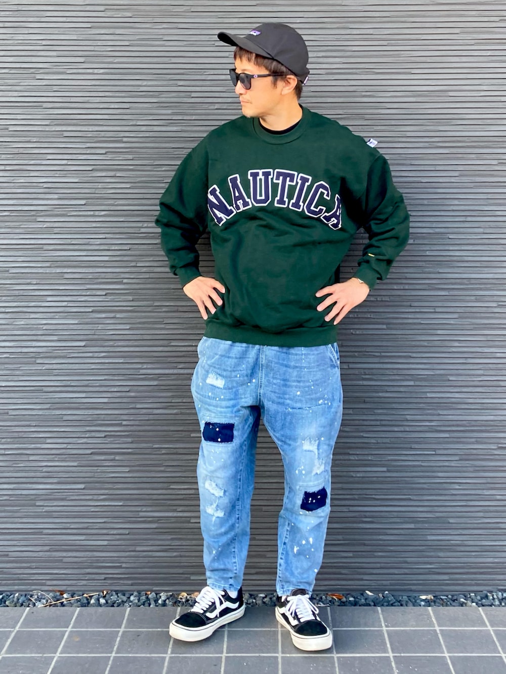 グリーン系のスウェット、ブルー系のデニムパンツ、ブラック系のスニーカーを着用したメンズの秋コーディネートの2枚目の写真