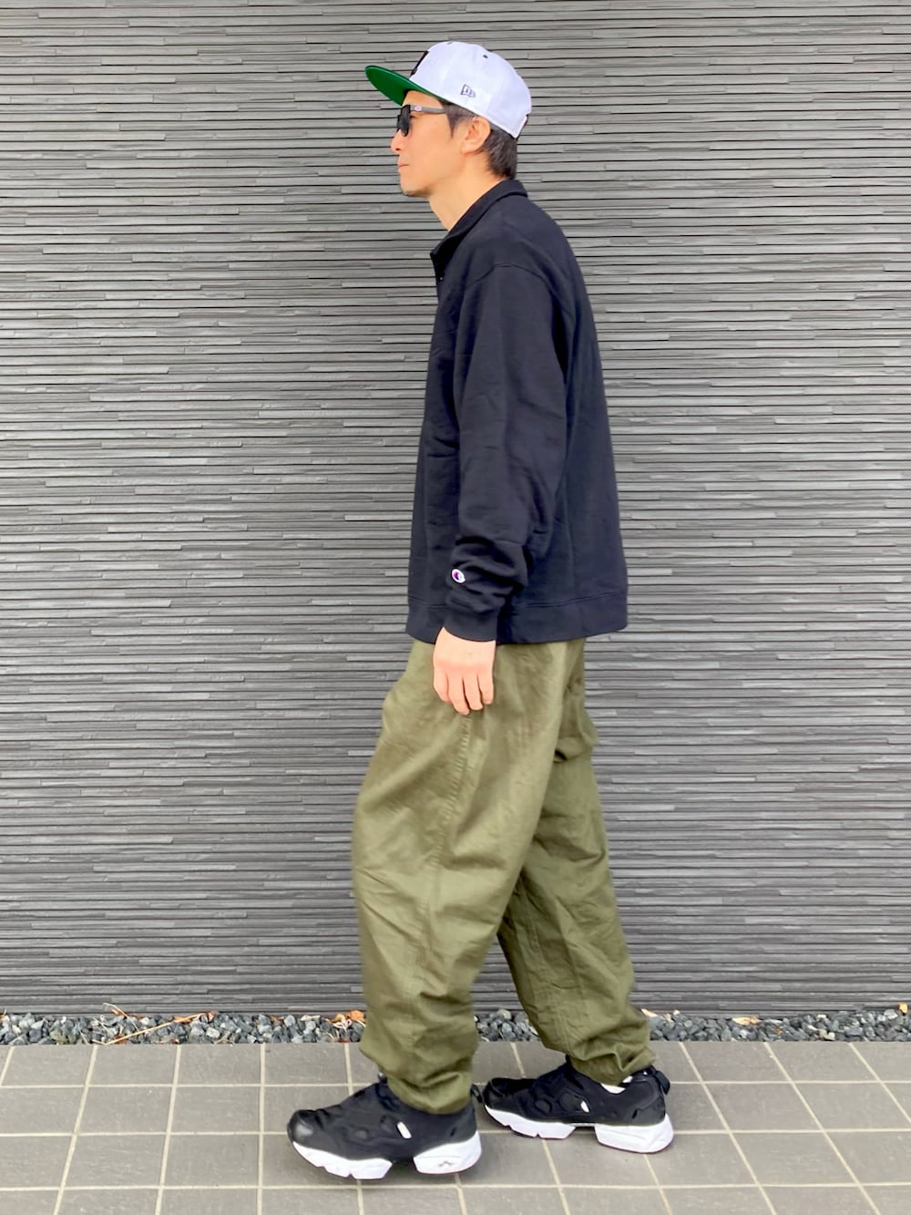 ブラック系のスウェット、グリーン系のチノパンツ、ブラック系のスニーカーを着用したメンズの春コーディネートの3枚目の写真