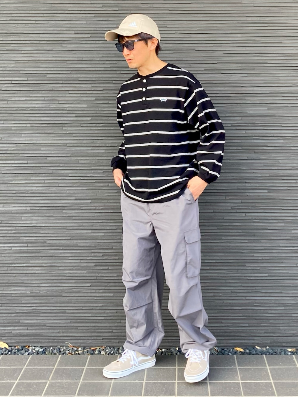 ブラック系のTシャツ/カットソー、グレー系のパンツ、ベージュ系のスニーカーを着用したメンズの春コーディネートの2枚目の写真