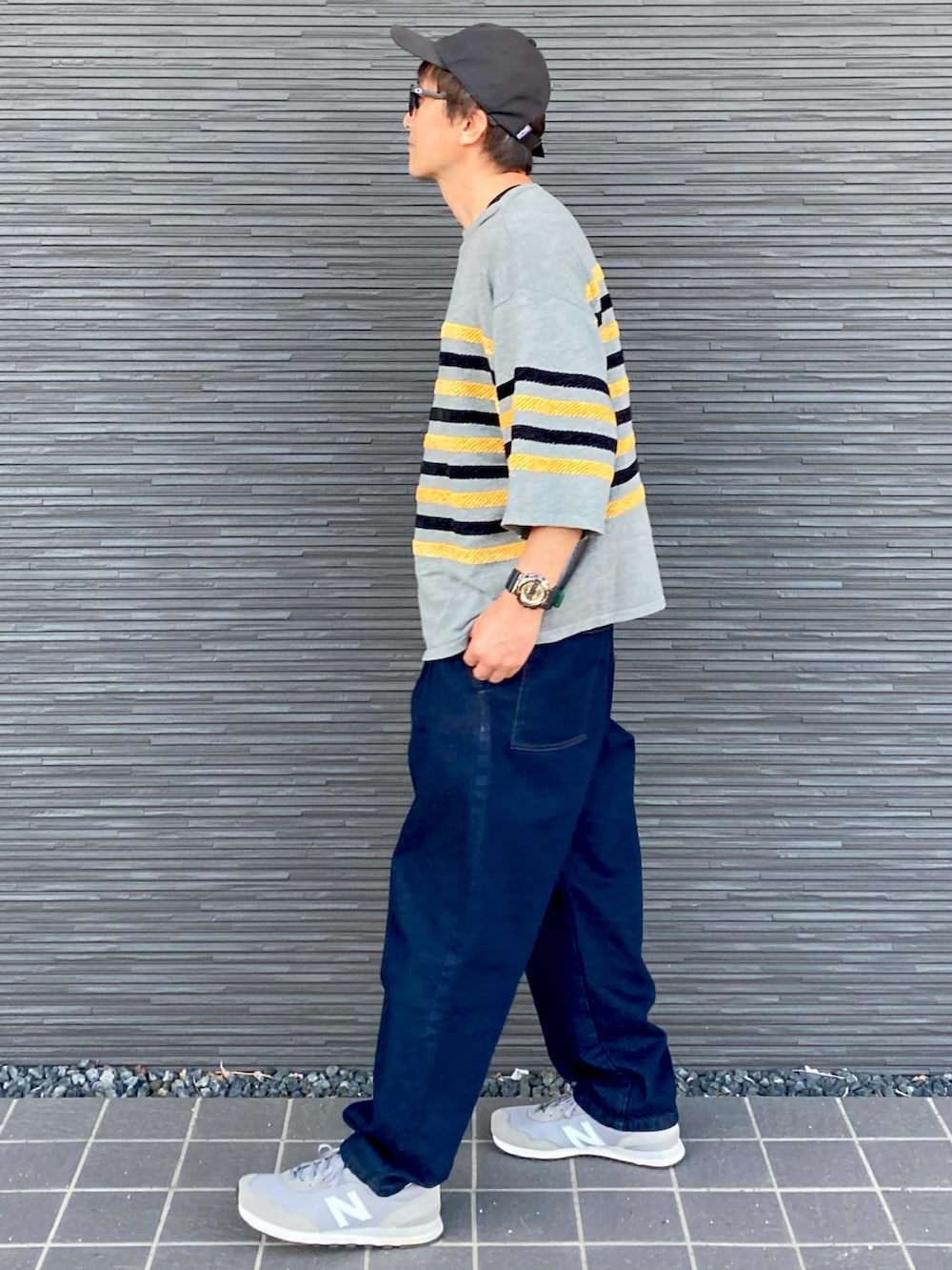 グレー系のニット/セーター、ブルー系のパンツ、グレー系のスニーカーを着用したメンズの秋コーディネートの2枚目の写真