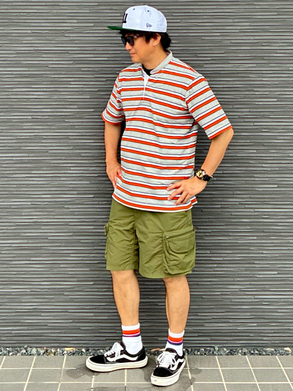 ブラック系のスニーカー、グレー系のTシャツ/カットソー、グリーン系のカーゴパンツを着用したメンズの夏コーディネートの2枚目の写真