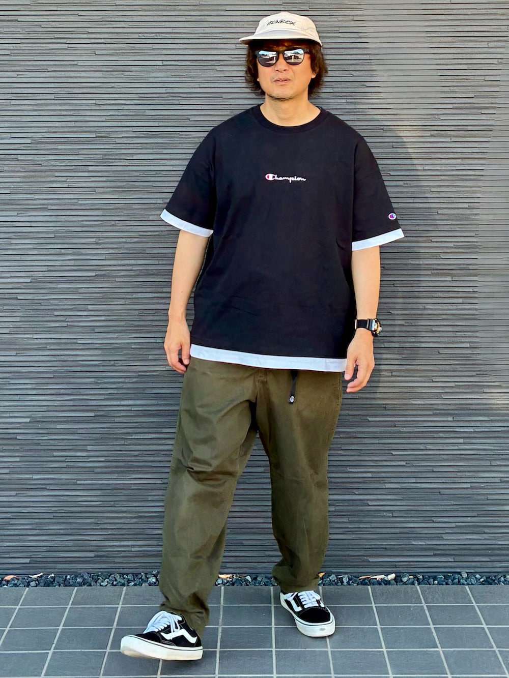 グリーン系のチノパンツ、ブラック系のスニーカー、ブラック系のTシャツ/カットソーを着用したメンズの夏コーディネートの4枚目の写真