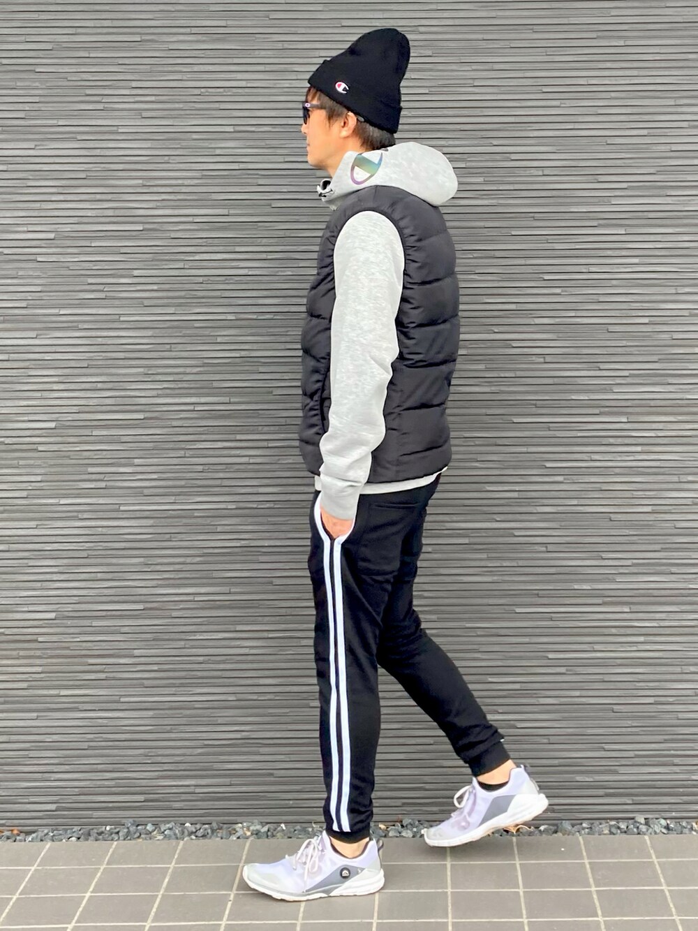 ブラック系のダウンベスト、グレー系のパーカー、ブラック系のスウェットパンツを着用したメンズの冬コーディネートの2枚目の写真