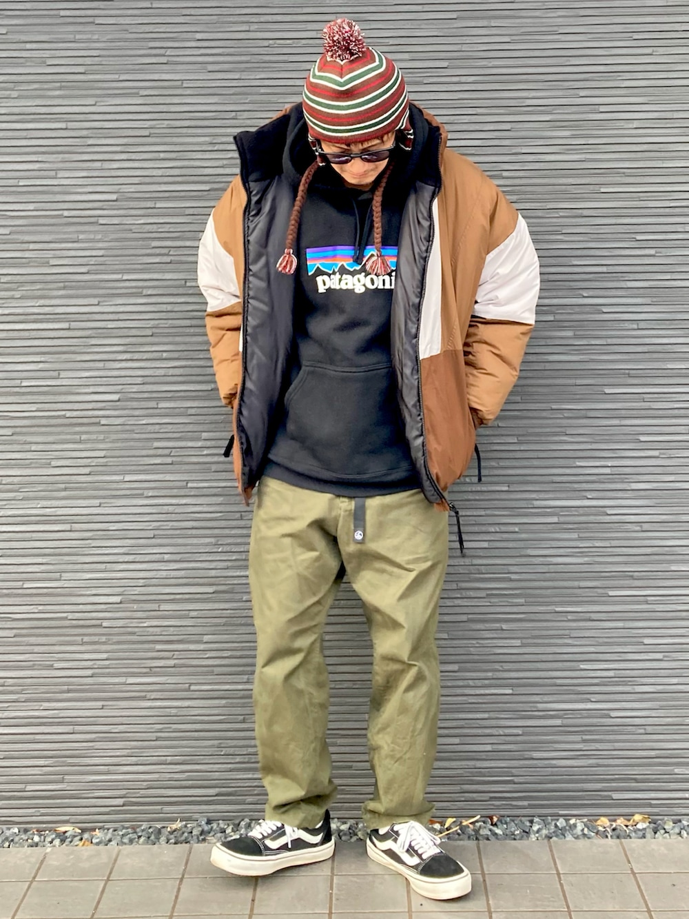 ベージュ系のブルゾン、ブラック系のパーカー、グリーン系のチノパンツを着用したメンズの冬コーディネートの3枚目の写真