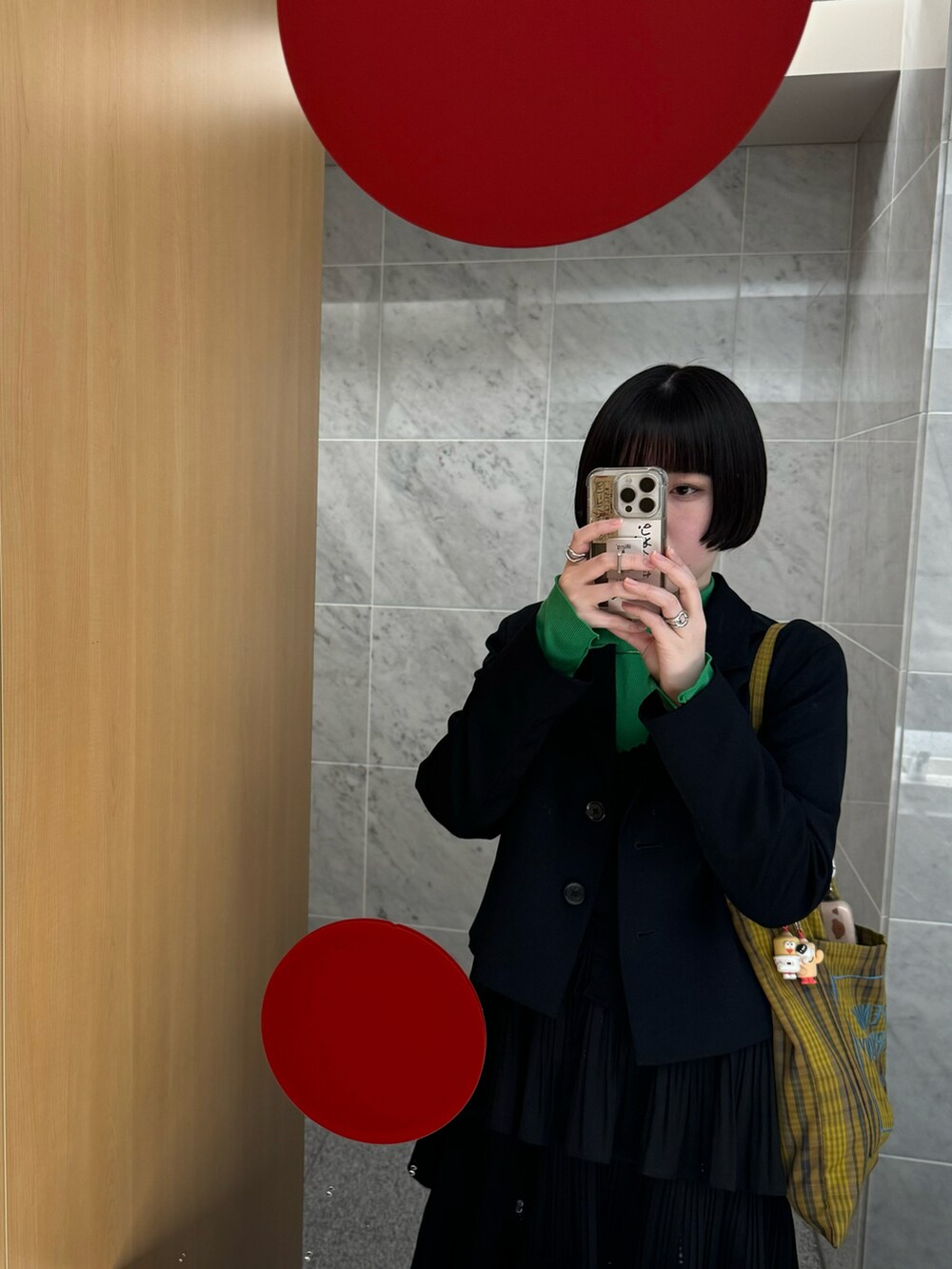 グリーン系のトップス、イエロー系のトートバッグ、ホワイト系のスカートを着用したレディースの春コーディネートの4枚目の写真