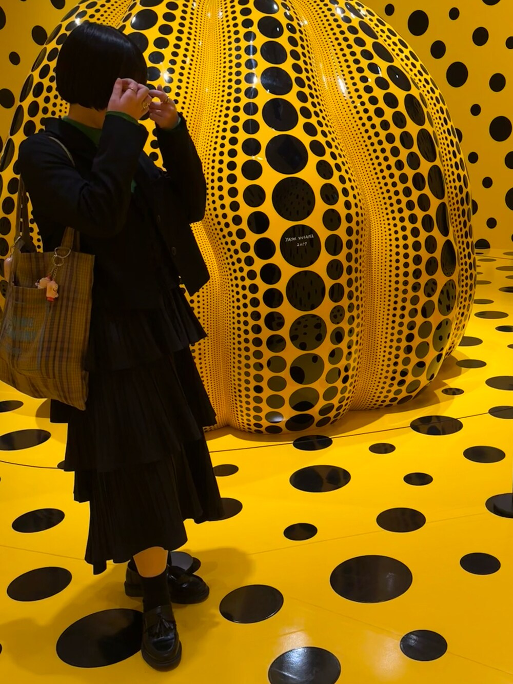 グリーン系のトップス、イエロー系のトートバッグ、ホワイト系のスカートを着用したレディースの春コーディネートの2枚目の写真