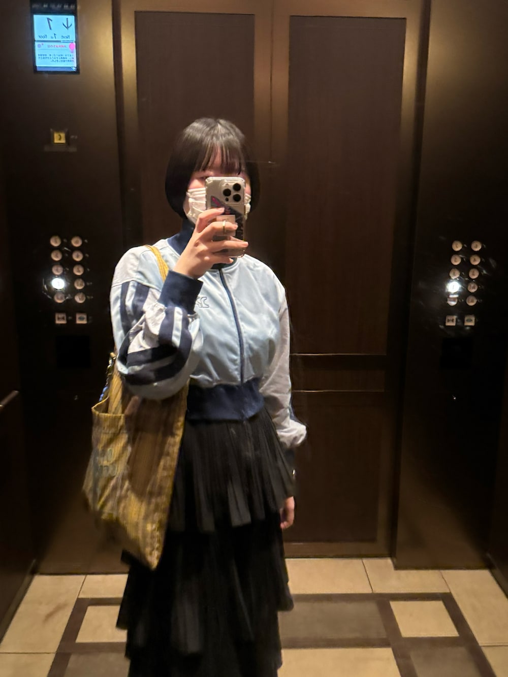 ブルー系のスニーカー、ホワイト系のスカート、ブルー系のナイロンジャケットを着用したレディースの春コーディネートの2枚目の写真