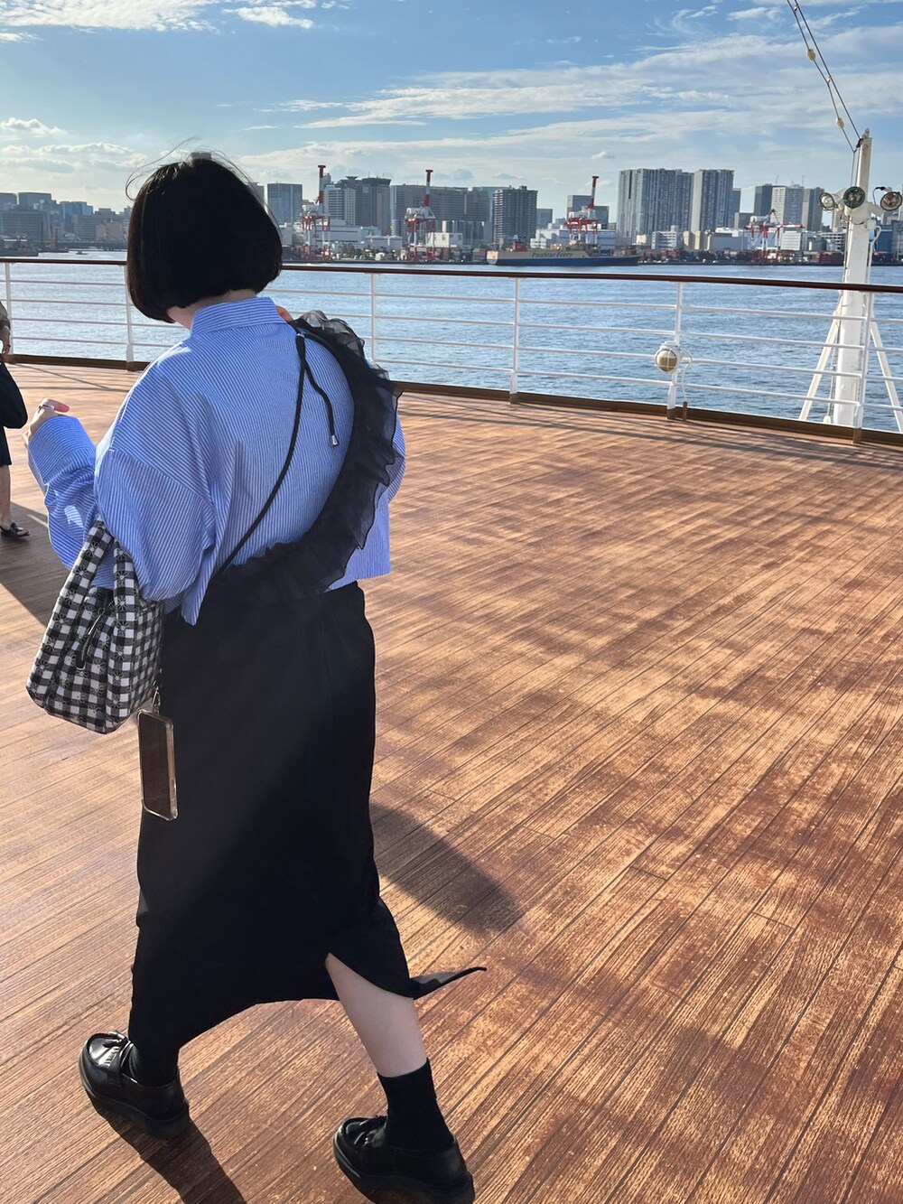 ブラック系のローファー、ブラック系のスカート、ブラック系のハンドバッグを着用したレディースの秋コーディネートの3枚目の写真