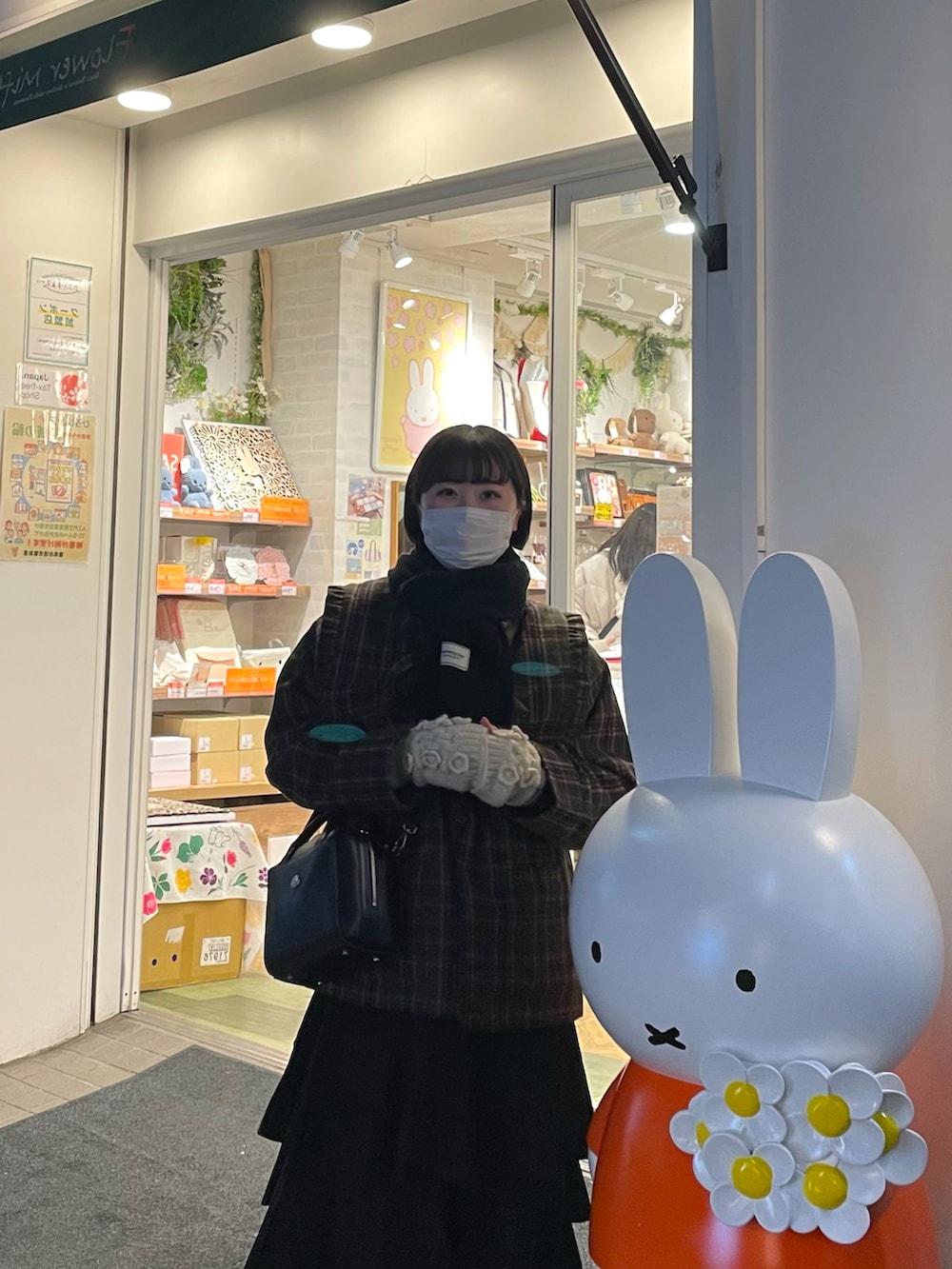 グリーン系のテーラードジャケット、ブラック系のショルダーバッグ、ホワイト系のスカートを着用したレディースの冬コーディネートの2枚目の写真