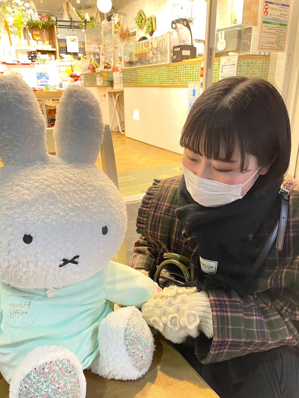 グリーン系のテーラードジャケット、ブラック系のショルダーバッグ、ホワイト系のスカートを着用したレディースの冬コーディネートの3枚目の写真