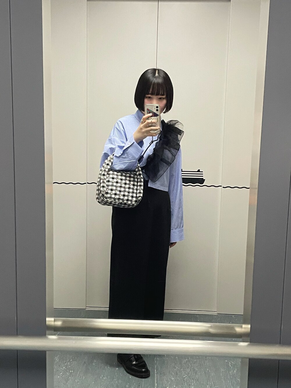 ブラック系のローファー、ブラック系のスカート、ブラック系のハンドバッグを着用したレディースの秋コーディネートの2枚目の写真