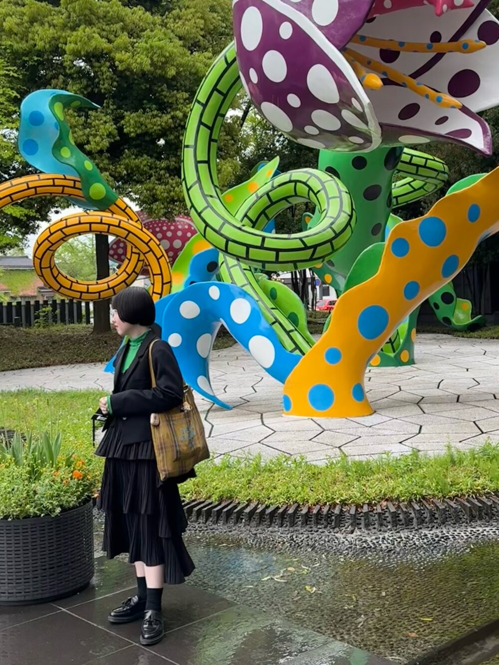 グリーン系のトップス、イエロー系のトートバッグ、ホワイト系のスカートを着用したレディースの春コーディネートの3枚目の写真